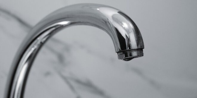 Verchromter Wasserhahn vor Marmorwand