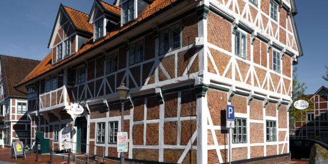Historisches Fachwerkhaus mit Backsteinfeldern und rotem Ziegeldach an einer Straße