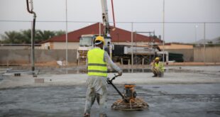 Bauarbeiter glättet frisch eingebrachten Estrich auf einer Baustelle mit einer Glättmaschine