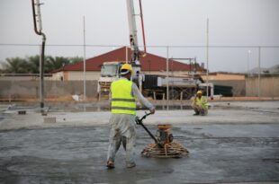 Bauarbeiter glättet frisch eingebrachten Estrich auf einer Baustelle mit einer Glättmaschine