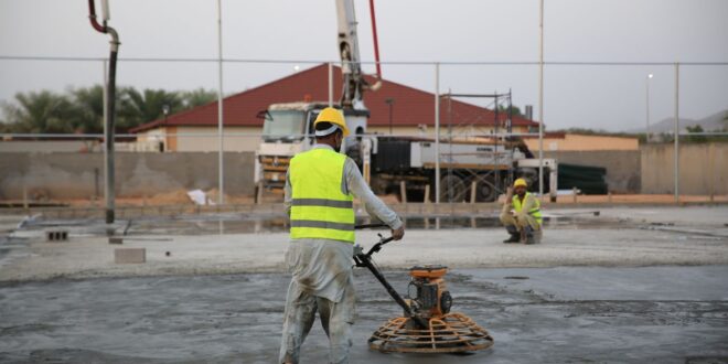 Bauarbeiter glättet frisch eingebrachten Estrich auf einer Baustelle mit einer Glättmaschine