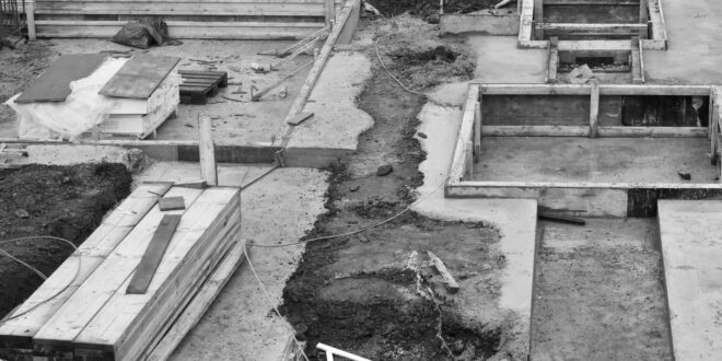 Baustelle in Schwarzweiß mit Schalungen und ausgehobenen Gräben für ein Fundament