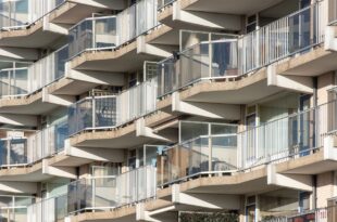 Mehrgeschossiges Wohngebäude mit Balkonen, deren Brüstungen aus Glas und Metallgeländern bestehen