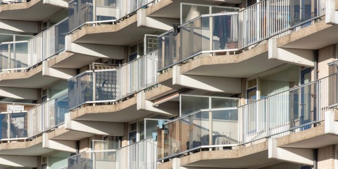 Mehrgeschossiges Wohngebäude mit Balkonen, deren Brüstungen aus Glas und Metallgeländern bestehen