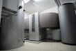 Heizraum mit Pufferspeicher, Warmwasserspeicher und Wärmepumpe an einer weißen Wand