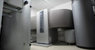 Heizraum mit Pufferspeicher, Warmwasserspeicher und Wärmepumpe an einer weißen Wand