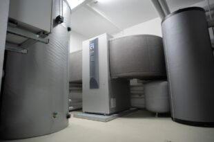 Heizraum mit Pufferspeicher, Warmwasserspeicher und Wärmepumpe an einer weißen Wand