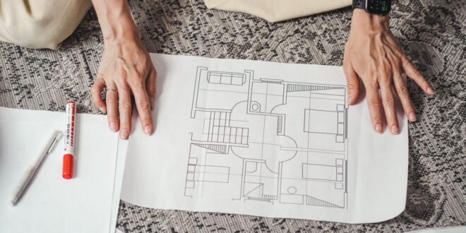 Grundriss-Plan auf Papier, Hände auf dem Bauplan