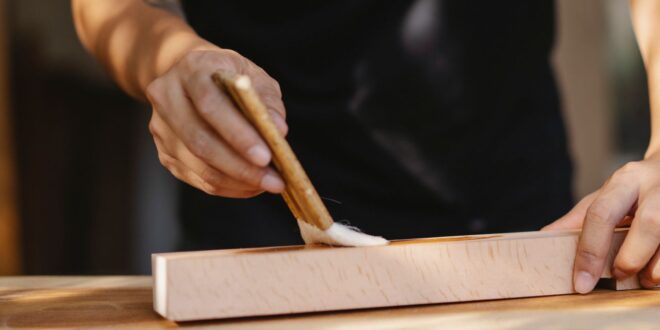 Holzbalken wird mit einem Pinsel imprägniert