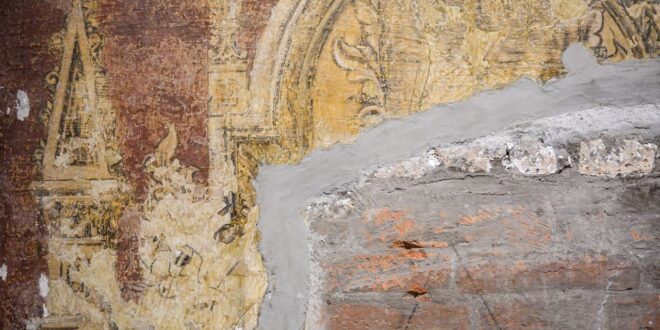 Alte Wand mit Wandmalereiresten, Ziegelmauerwerk und frisch aufgetragener heller Putzausbesserung
