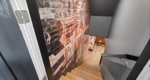 Treppe in einen Keller hinab mit freiliegender Ziegelwand und Holzstufen