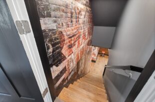 Treppe in einen Keller hinab mit freiliegender Ziegelwand und Holzstufen
