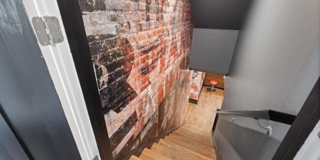 Treppe in einen Keller hinab mit freiliegender Ziegelwand und Holzstufen