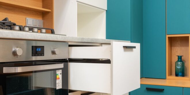Offene Schublade eines Küchenschranks neben Backofen