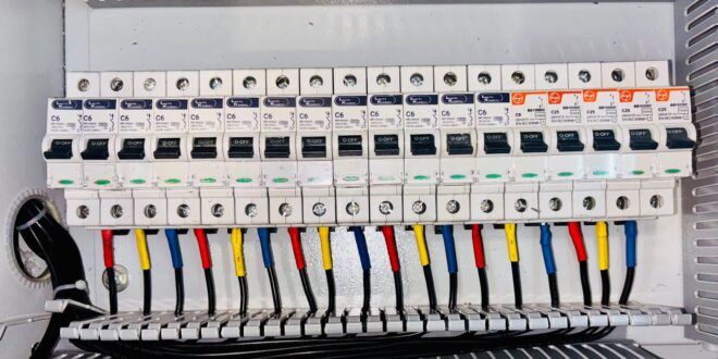 Geöffneter Verteilerkasten mit einer Reihe von Leitungsschutzschaltern und farbig gekennzeichneten Leitungen