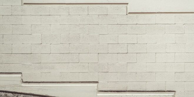 Helle Betonsteinwand mit abgeschrägtem Betonsockel am unteren Rand