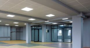 Große Halle mit abgehängter Rasterdecke aus hellen Platten und eingebauten LED-Panels, graue Stützen