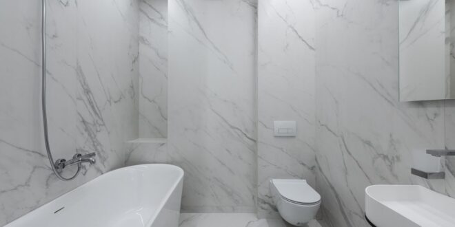 Weißes Marmorbad mit wandhängendem WC, Betätigungsplatte, Badewanne und Waschtisch