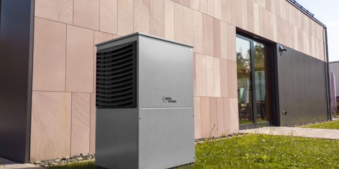 Außengerät einer Luft-Wasser-Wärmepumpe vor einem modernen Wohnhaus