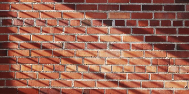 Rote Ziegelwand mit Sonnenlicht und Schattenstreifen