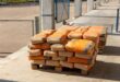 Gestapelte Zementsäcke mit orangefarbenem Aufdruck auf einer Holzpalette im Freien